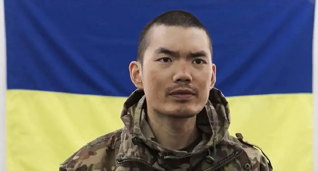 Полонений боєць із Китаю на фоні українського прапора