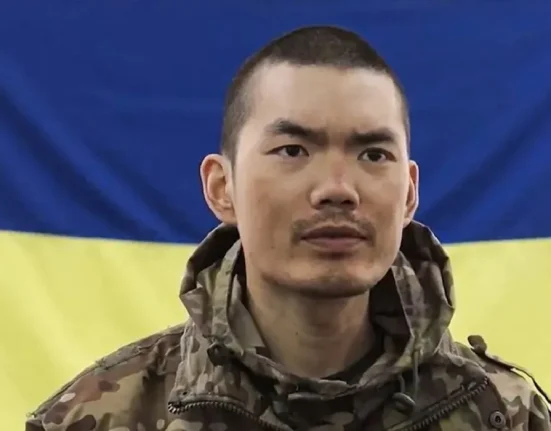 Полонений боєць із Китаю на фоні українського прапора