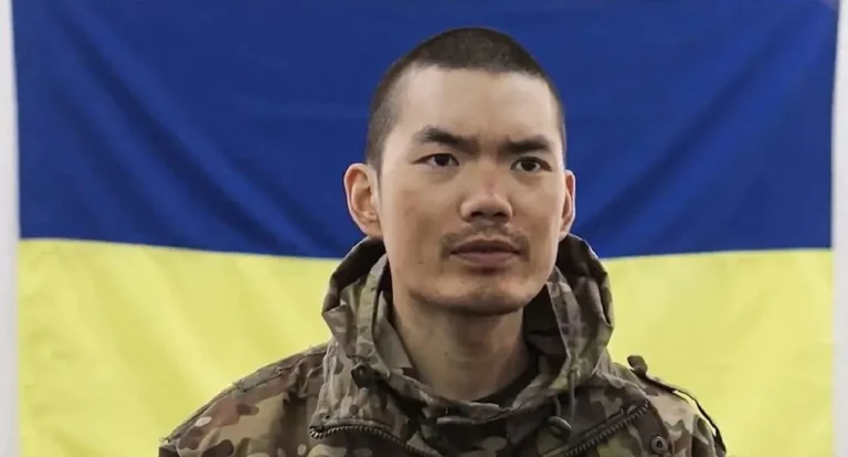 Полонений боєць із Китаю на фоні українського прапора