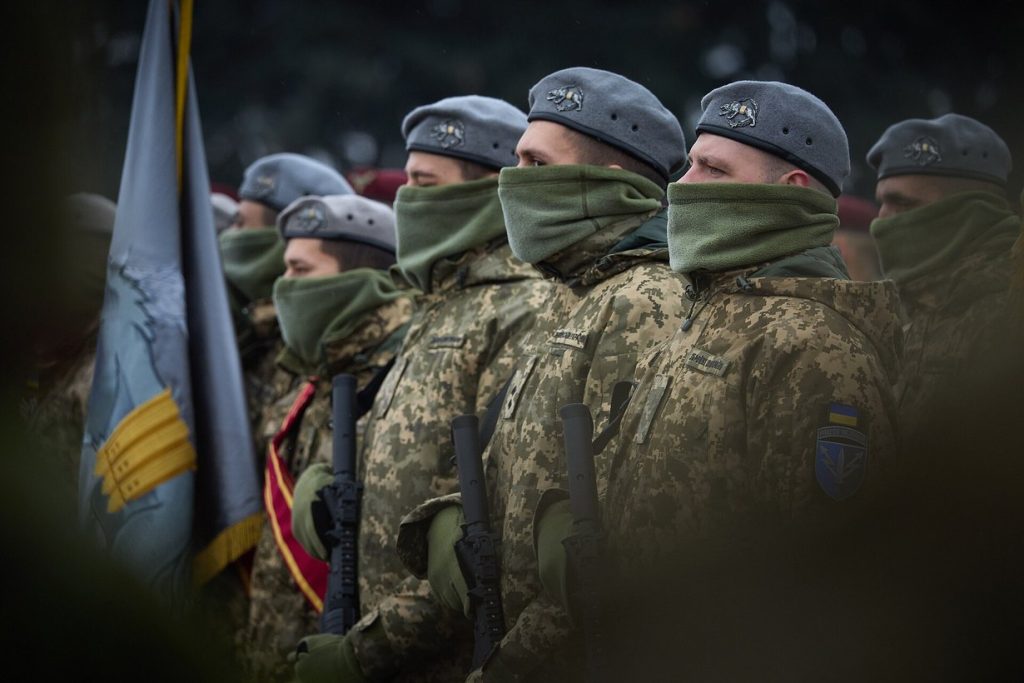 Українські військові в строю з бойовим прапором під час урочистостей до Дня ЗСУ