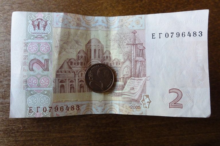 Банкнота 2 гривні та монета на дерев'яному столі